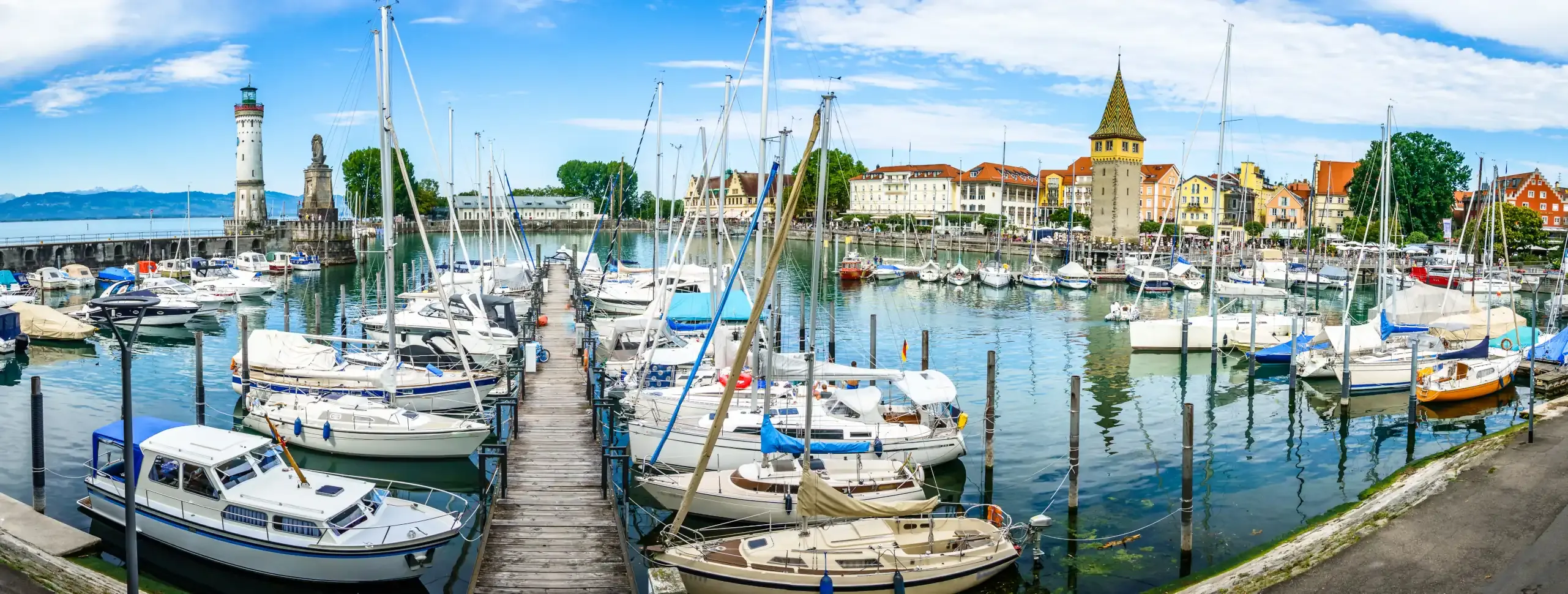 Ansicht des Lindauer Hafens am Bodensee mit Leuchtturm und viele Motor- und Segelbooten